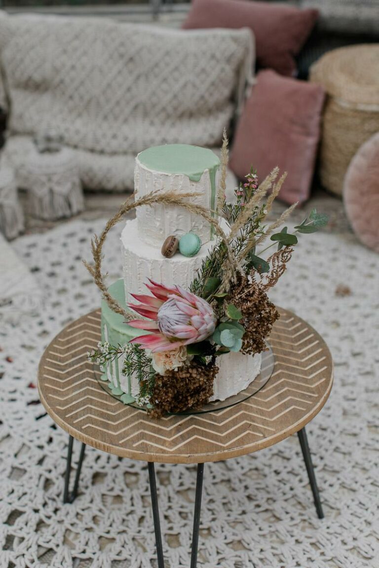 Dreistöckige weiße Hochzeitstorte mit minfarbenen Drip und Blumenbouqet mit Prothea, Pampasgras